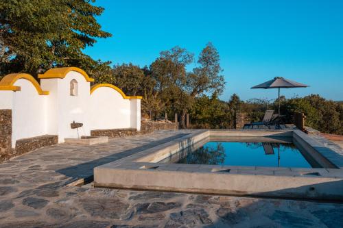 a swimming pool with an umbrella next to a church at Casa do Vale in Marvão