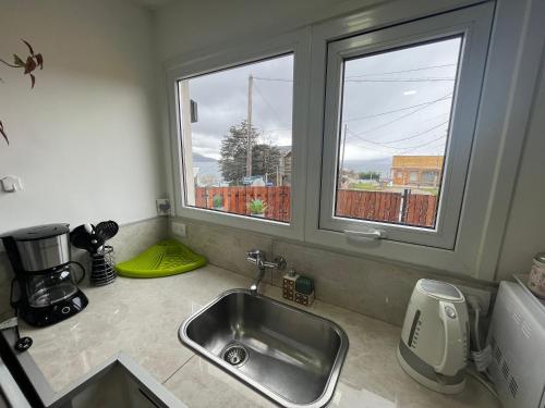 a kitchen with a sink and two windows at VISTA AL FARO Ushuaia in Ushuaia