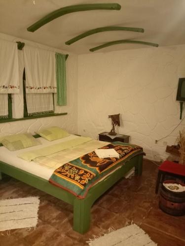 ein Schlafzimmer mit einem grünen Bett in einem Zimmer in der Unterkunft BUMBAR ETNO DVORAC in Tekija