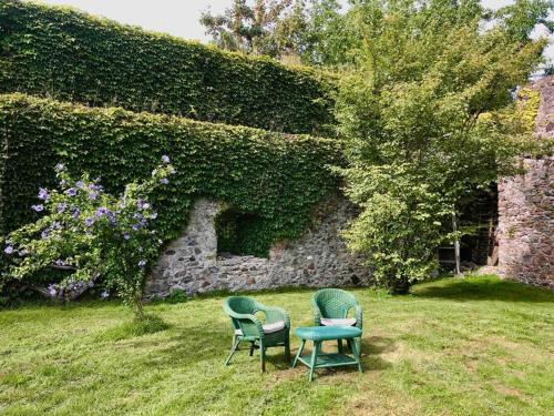 2 chaises et une table en face d'un mur en pierre dans l'établissement Urlaub in der Burg am Bodensee, à Kressbronn am Bodensee
