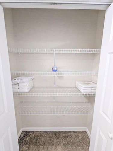 a white closet with white shelves and towels at Luxury Stylish Townhome King Beds WD Garage in Schenectady