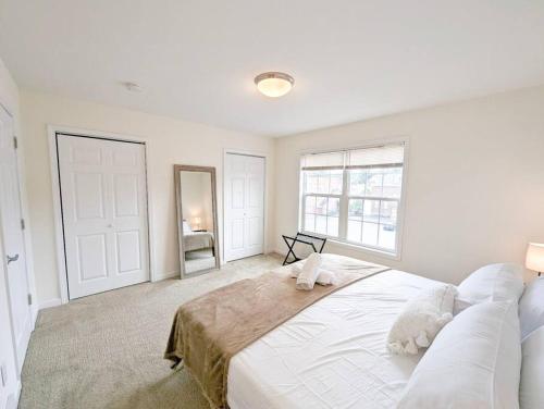 a white bedroom with a large bed and a mirror at Luxury Stylish Townhome King Beds WD Garage in Schenectady