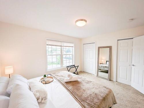 een woonkamer met een witte bank en een spiegel bij Luxury & Stylish Townhome, King Beds, W/D, Garage in Schenectady