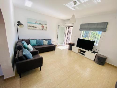 a living room with a couch and a television at Stunning mountain views! Private Villa with fabulous communal pool! in Murla