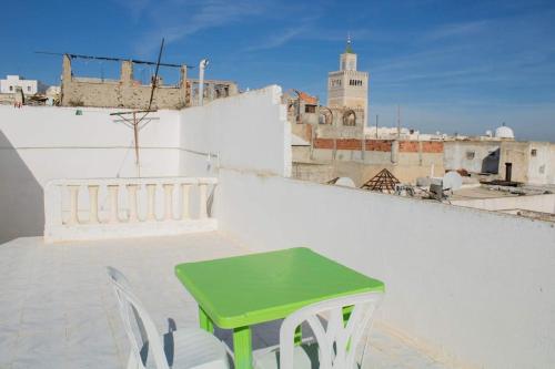 a green table and two white chairs on a roof at Superbe appartement en plein médina de Tunis in Tunis