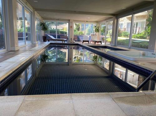 una piscina cubierta en una casa con bañera en MRG Luxo e Tranquilidade Casa de Pedra 2D, en Gramado