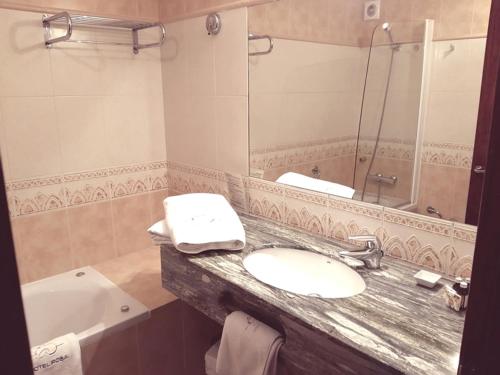 a bathroom with two sinks and a tub and a mirror at Hotel Rosa & Spa Begur in Begur