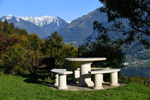 a picnic table and a chair on a lawn with mountains at Ferienhaus auf dem Lamahof in Stalden