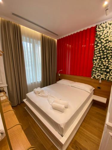 una camera con un letto bianco con una parete rossa di Peaky Hotel a Durrës