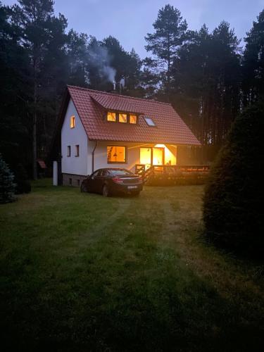 a house with a car in the yard at night at Domek Leśny Reset in Studzienice