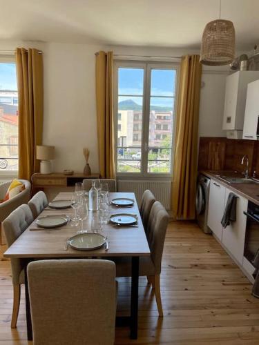 une table de salle à manger avec des chaises et une grande fenêtre dans l'établissement T3 de charme au centre de Clermont, à Clermont-Ferrand