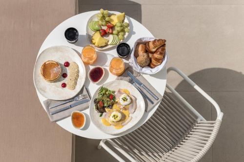 a white table with plates of food on it at Enigma Suites in Fira