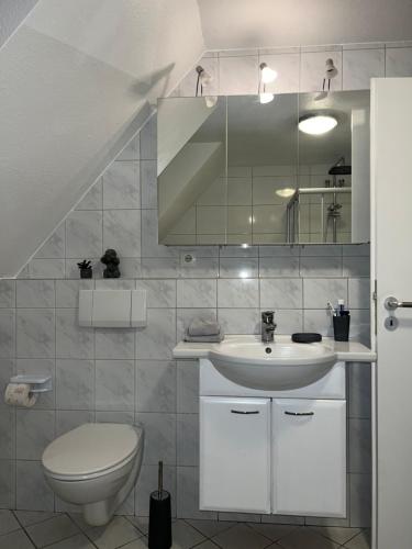 a white bathroom with a sink and a toilet at Apartment by Harbali in Schüttorf