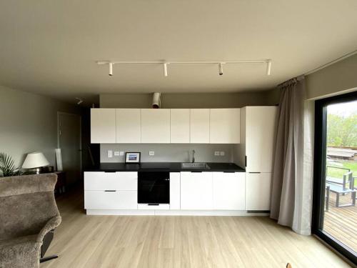 una cucina con mobili bianchi e un divano in una stanza di Leilighet med nydelig utsikt a Tromsø