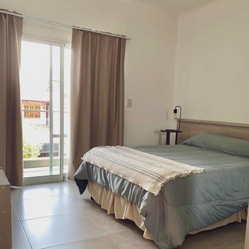 a bedroom with a bed and a large window at Departamentos Fleming, luminosos p hasta 4 personas in Paraná