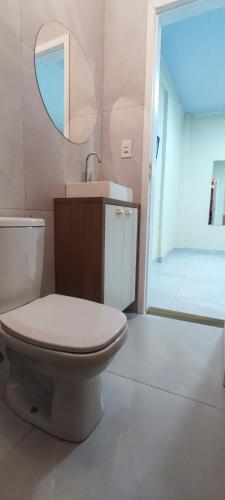 a bathroom with a toilet and a sink and a mirror at Quarto privativo in Foz do Iguaçu