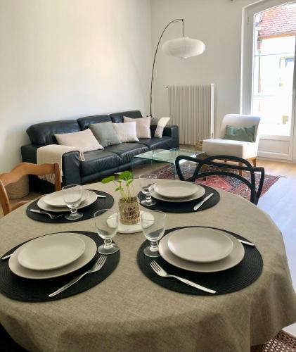 - une table avec des assiettes et de l'argenterie dans le salon dans l'établissement Appartement Coeur de Ville Cathédrale - Ascenseur -, à Colmar