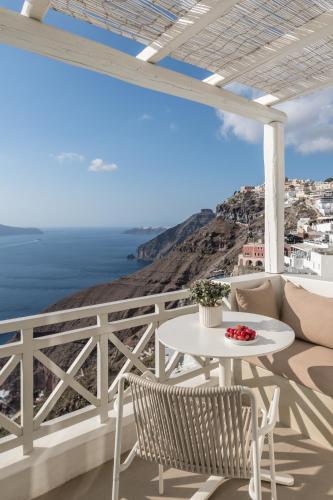 a white table and chairs on a balcony with the ocean at Enigma Suites in Fira