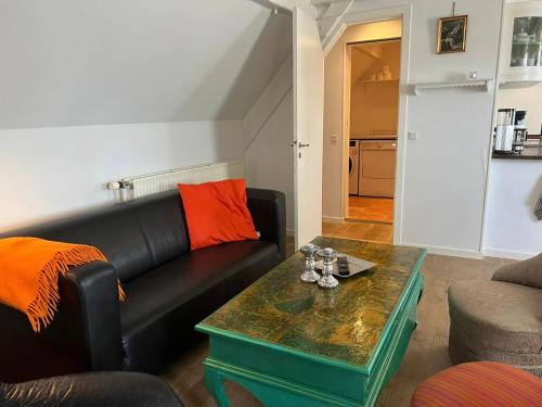 a living room with a black couch and a table at Skovridergaardens Ferielejligheder in Aabenraa