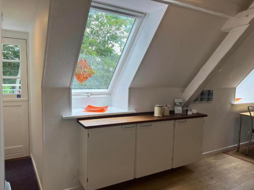 an attic kitchen with a window and white cabinets at Skovridergaardens Ferielejligheder in Aabenraa