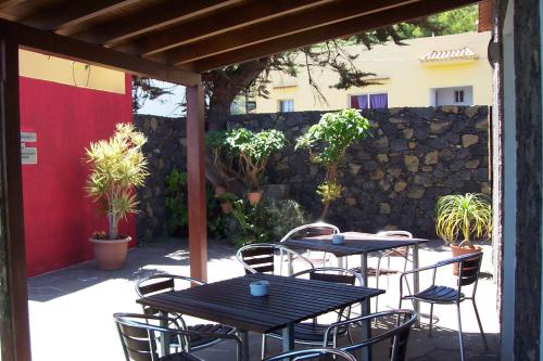 a patio with tables and chairs and a stone wall at Hotel Villa El Mocanal in Mocanal