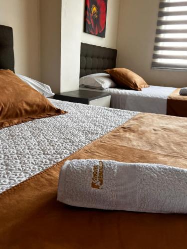 two beds in a hotel room with a towel on them at Hotel Ebenezer in Santo Domingo de los Colorados