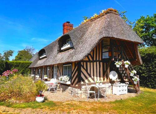 a thatched cottage with a thatched roof at La Romance et la Romanesque in Berville-sur-Mer