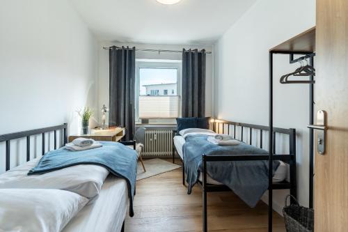 two beds in a small room with a window at Krause: deine Wohlfühloase in Zentrum v. Bielefeld in Bielefeld