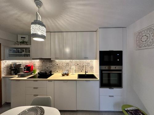 a kitchen with white cabinets and black appliances at Casa Magnolia Patras in Patra