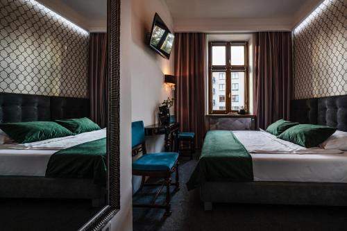 クラクフにあるAparthotel Maargickのベッド2台と鏡が備わるホテルルームです。