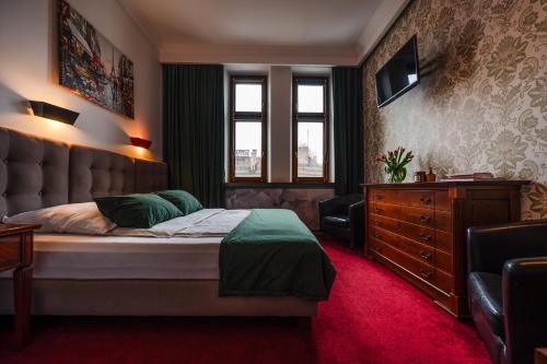 ein Schlafzimmer mit einem Bett, einer Kommode und einem Fenster in der Unterkunft Aparthotel Maargick in Krakau