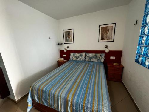 een slaapkamer met een bed met een gestreepte sprei bij Beach Morro Jable Fuerteventura in Morro del Jable