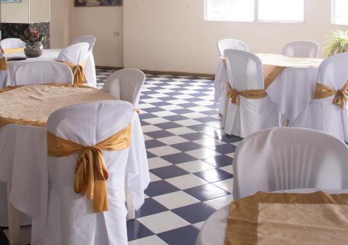 a room with white chairs and tables with bows at Hotel Ebenezer in Santo Domingo de los Colorados