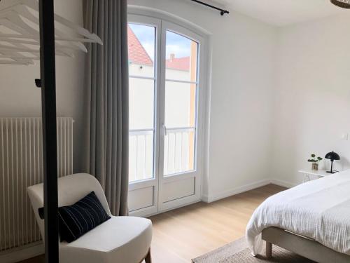1 dormitorio con 1 cama, 1 silla y 1 ventana en Appartement Coeur de Ville Cathédrale - Ascenseur -, en Colmar