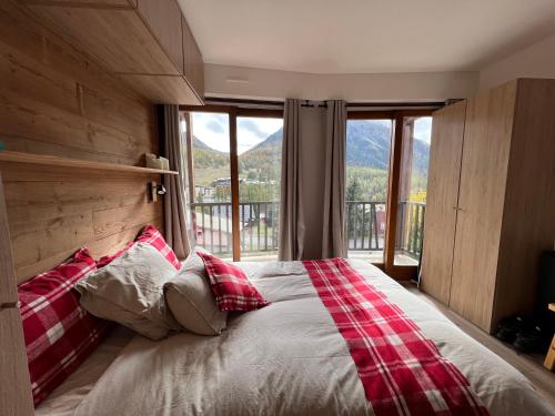 una camera da letto con un grande letto con una grande finestra di La Marmotte Duplex 4 p. entièrement rénové avec vue magnifique a Monginevro