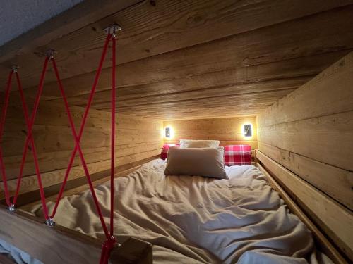 a bed in a wooden room with red ropes at Les Tanières de Montgenèvre - La Marmotte - Duplex 4 p entièrement rénové avec vue magnifique in Montgenèvre