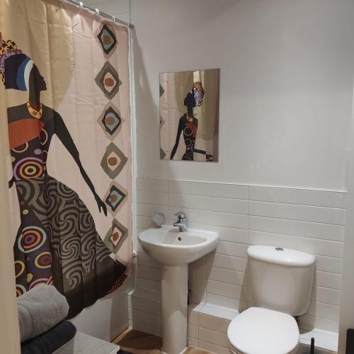 a bathroom with a sink and a toilet and a shower curtain at Ratcliffe Apartment in Colchester