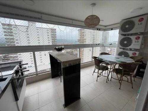 uma cozinha com uma mesa e uma grande janela em Prainha, Feirinha, Tranquilidade! na Praia Grande