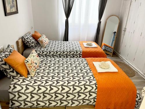 um quarto com 2 camas com lençóis cor-de-laranja e preto em Alzira bonita Apartamento B con patio, la Casella em Alzira