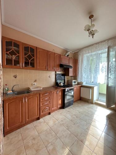 a kitchen with wooden cabinets and a large window at Апартаменти біля обласної лікарні in Lutsk