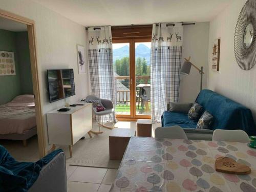 un salon avec un canapé bleu et une table dans l'établissement T2 au pied des pistes de La Joue du Loup avec piscine et sauna, à Saint-Étienne-en-Dévoluy