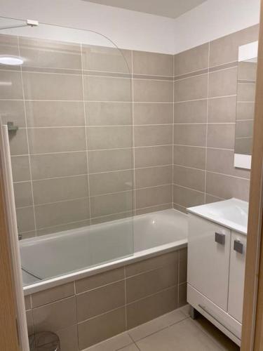 une salle de bain avec une baignoire et un lavabo et une baignoire dans l'établissement T2 au pied des pistes de La Joue du Loup avec piscine et sauna, à Saint-Étienne-en-Dévoluy