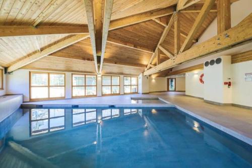 une grande piscine intérieure avec un plafond en bois dans l'établissement T2 au pied des pistes de La Joue du Loup avec piscine et sauna, à Saint-Étienne-en-Dévoluy