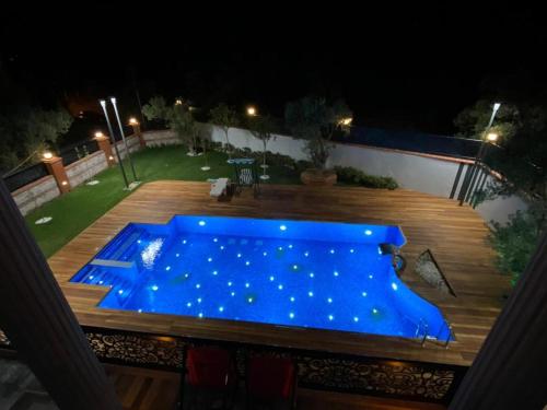 uma piscina azul num deque de madeira à noite em Cunda Eye em Ayvalik