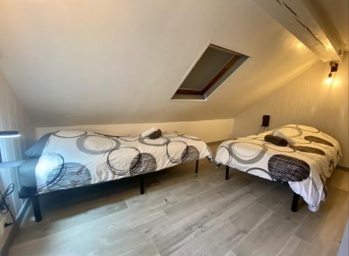 two beds in a room with a roof at Le P'tit Rupt Refuge cocooning in Rupt-sur-Moselle