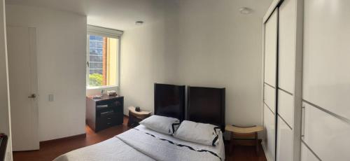 um quarto com uma cama e uma janela em Acogedor apartamento en zona corporativa Ciudad Salitre em Bogotá