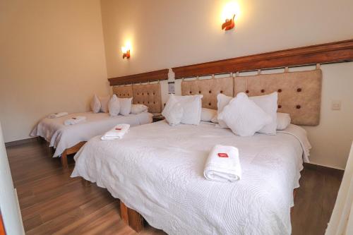 two beds in a hotel room with white sheets at Hotel las Palmas in Villa de Leyva