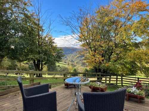 a patio with two chairs and a table on a wooden deck at Weather Hill Cottage, Hebden Bridge in Hebden Bridge