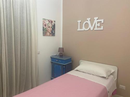un dormitorio con una cama y un cartel que diga amor en La casa di Luana sulla via Francigena, en Monterosi