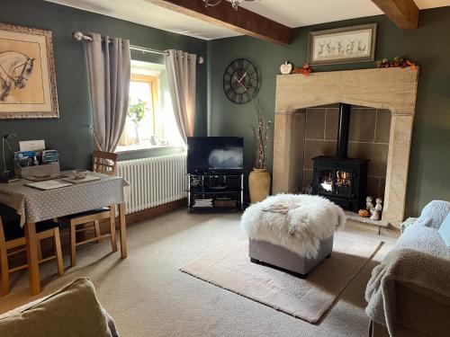 a living room with a fireplace and a table and a couch at Weather Hill Cottage, Hebden Bridge in Hebden Bridge